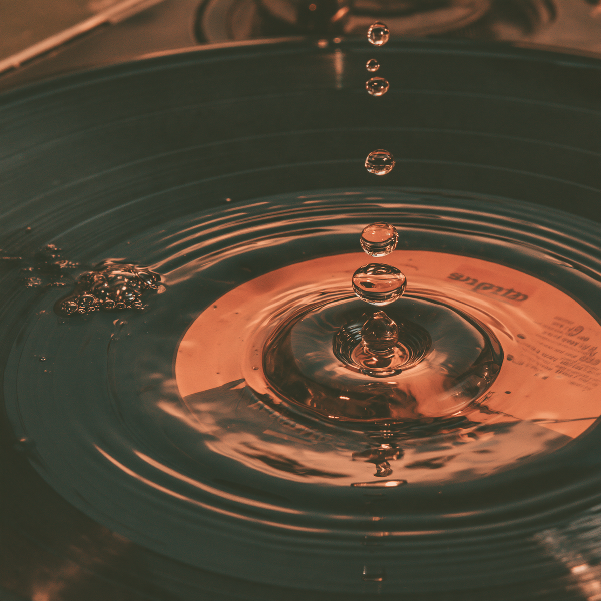 Liquid chrome drop rippling on black vinyl